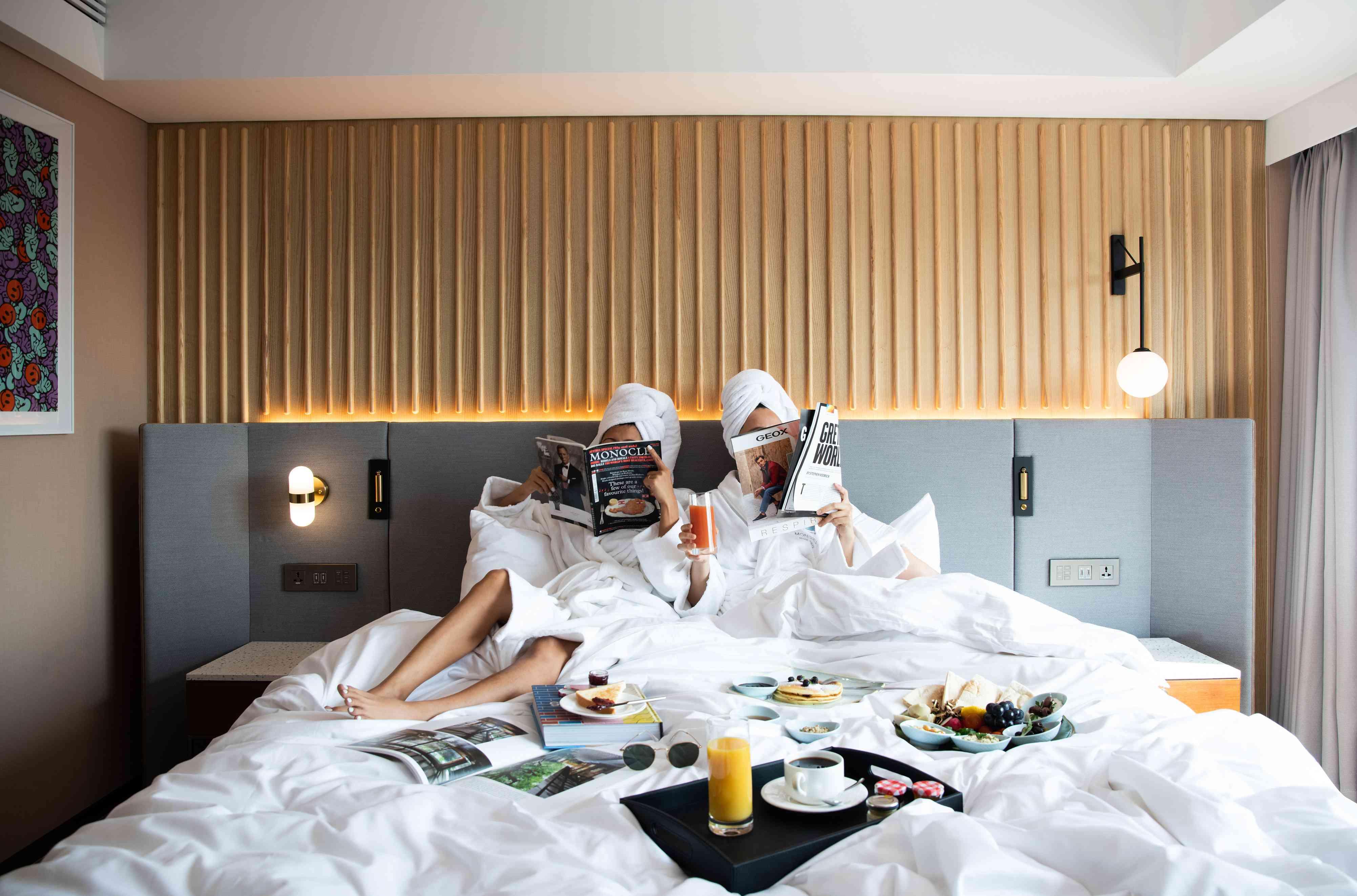 pessoas na cama do hotel com café da manhã